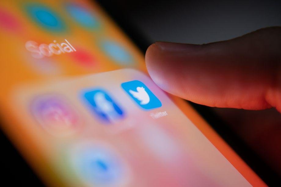 Bangkok, Thailand - July 14, 2019 : iPhone user touching Twitter Multilingual publics in the Corona vaccination debate on Twitter